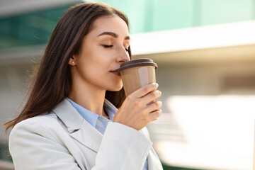 Calm pretty millennial european woman drink cup of coffee takeaway, with closed eyes