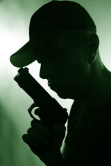 Young criminal killer in cap with gun