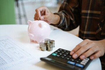 Saving money. hand putting money into pink piggy bank making investments or strategy for personal...