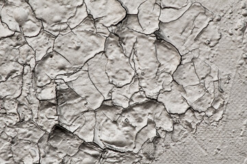 Old and cracked paint on a wall needs repair and renovation. Thick layer of paint cracked because of weather and humidity shows the aging process. Empty background for renovation paint company