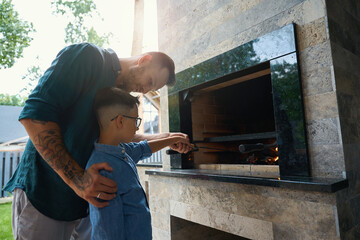 Man and his son cook over a fire on terrace