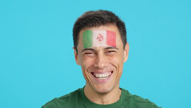 Man with a mexican flag painted on the face smiling
