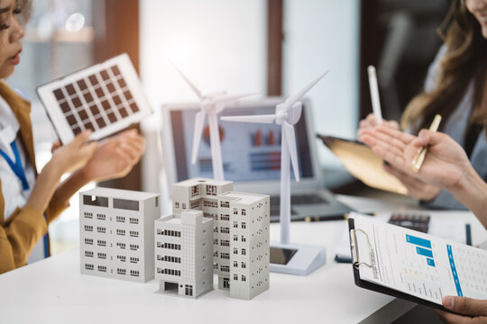 Businessman and designer working making model apartments. with blueprints for sketching a construction project, green energy and solar panel concept. - Powered by Adobe