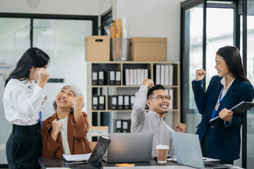Successful business team, excited young people Keeping up arms and showing positive emotions, happy working in modern office on computer.