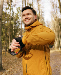 A man in sportswear uses an active lifestyle fitness bracelet. A human jogging instructor is hardy...