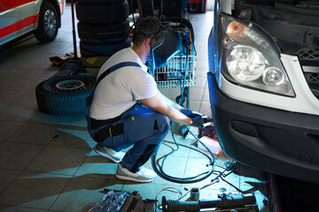Experienced automotive service technician is repairing customer van - obrazy, fototapety, plakaty