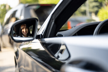 Portrait of a beautiful woman sitting in luxury car, view on through a side mirror. Concept of business transfer services, chauffeur portrait or business trips