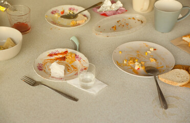 Empty dirty plates with spoons and forks on the table after meal. Banquet ending concept. Unwashed dishes ready to cleaning