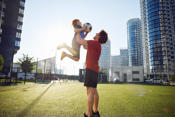 Happy father throwing excited son child in air after training football