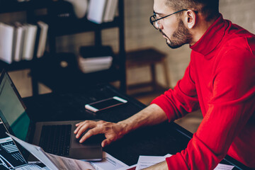 serious hipster guy in casual look checking information on website