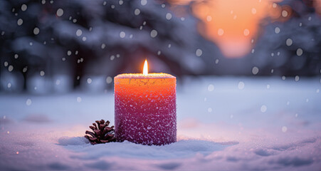 vela de navidad encendida junto a piña sobre paisaje natural de bosque nevando y fondo de atardecer desenfocado