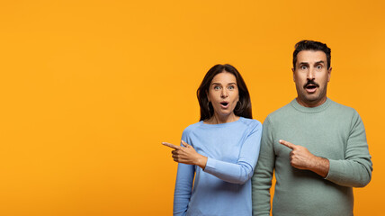 Shocked senior european husband and wife in casual point finger at free space