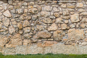 Old stone wall background texture. The building exterior is made of different sized rocks and cement in between. Natural material was used for the ancient construction.
