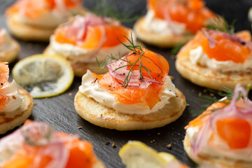Mini blini pancakes with soft cheese, cold smoked salmon and dill