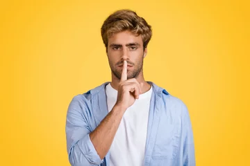 Foto op Plexiglas Serious european man gesturing silence on yellow backdrop © Prostock-studio