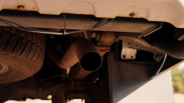 A close-up shot of the exhaust pipe of an SUV car with water splashing out when engine is started