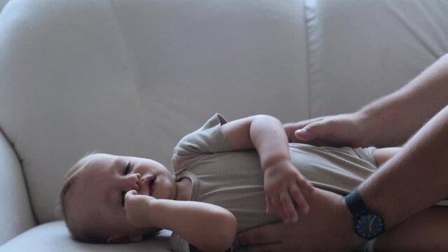 The kid is naughty lying on the couch next to dad. Poor health and whims of the baby.