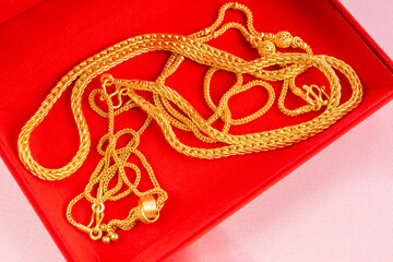 Group of gold necklaces in red velvet box.