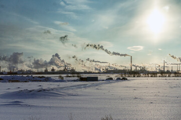 industrial winter scenery: smoke and steam from oil refinery, steel mill, and power plant on a...