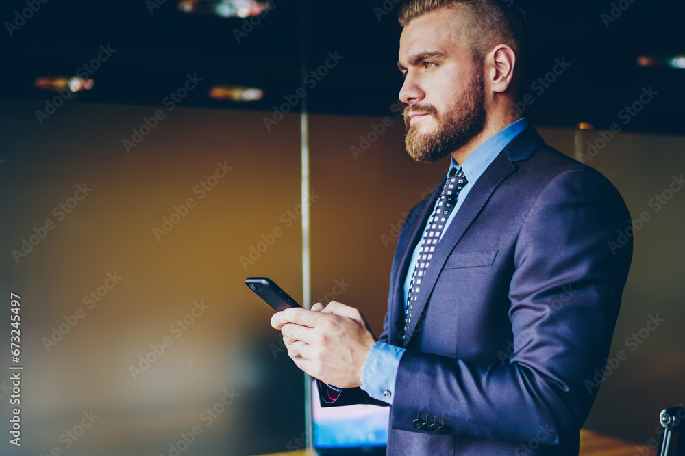 Poster serious businessman messaging on cellular, checking online banking via application