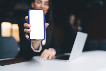 Unrecognizable woman with mobile phone sitting at table in office