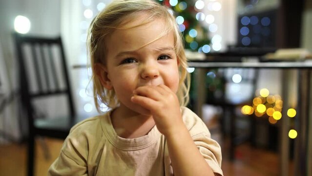 Little smiling girl eating christmas cookies and waving her hands