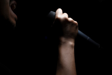A male singer is shouting and holding a microphone in his hand.