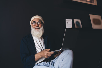 Cheerful senior man sitting with laptop