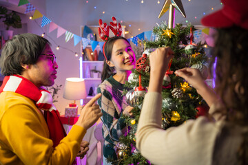 Group of Asian friends Decorating the christmas tree at home.