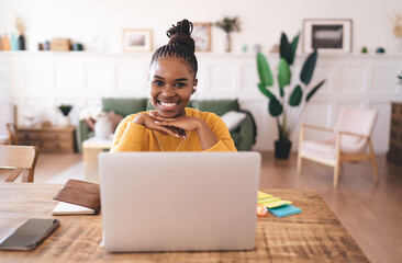 Smiling black woman sitting at table with laptop