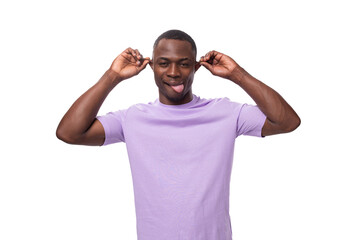 Fototapeta premium young cheerful african man with a short haircut dressed in a lilac t-shirt makes a grimace