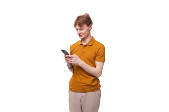 portrait of a young guy with short red hair dressed in a summer T-shirt with a smartphone in his hand