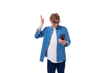 young smart european man with copper hair wears a denim shirt writes a message in the phone