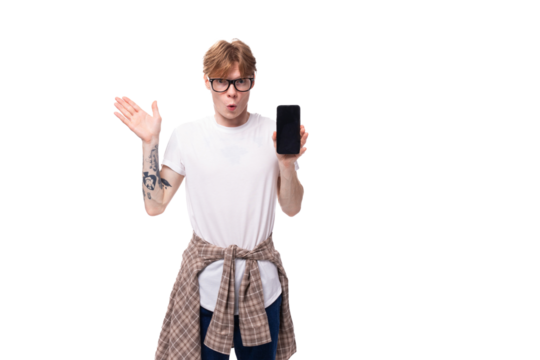 young surprised european red-haired guy in a t-shirt shows a vertical smartphone