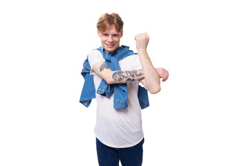 young handsome caucasian man with golden red hair with a tattoo on his arms is dressed in a white t-shirt