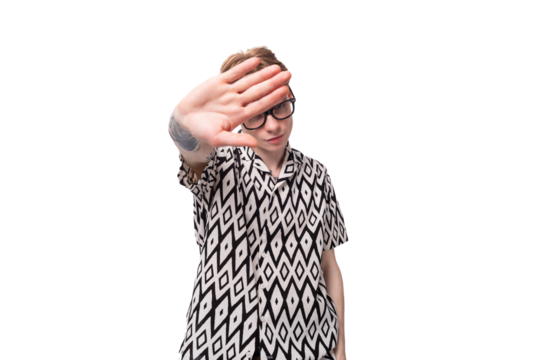 young european male student with red hair dressed in a shirt with a rhombus pattern shows a stop gesture