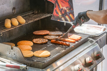 Process of cooking meat for burgers and cheeseburgers, sausages for hot dogs, buns on a grill with...