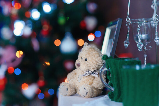 Christmas and New Year home decoration, fluffy teddy bear on foreground and Christmas lights on background. Christmas mood and atmosphere.