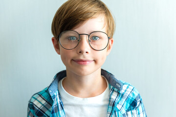 Vision correction for children. Smiling child boy with stylish eyeglasses on light gray background