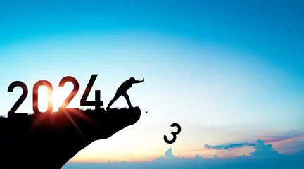 Fotobehang Silhouette man pushing number 3 from cliff with 2024 on blue sky for preparation merry Christmas and happy new year from 2023 to 2024 concept. © Dilok