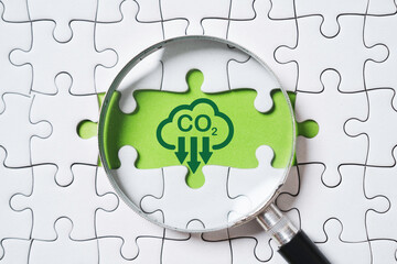 Magnifier glass with CO2 reduction on green background and jigsaw for decrease CO2 , carbon...