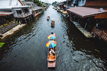 Fototapeta premium Samut Songkhram Thailand– November 05, 2023: Wooden boats busy ferrying people at Amphawa floating market A traditional popular method of buying and selling is still practiced in Amphawa.