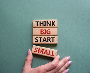 Think big start small symbol. Concept words Think big start small on wooden blocks. Beautiful grey green background. Businessman hand. Business and Think big start small concept. Copy space