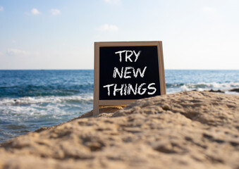 Try new Things symbol. Concept words Try new Things on black chalk blackboard blocks. Beautiful sea...