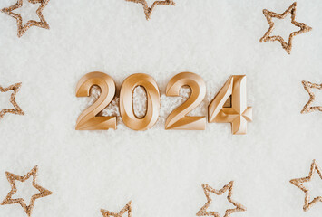 Greeting card - happy new year with numbers 2024 and gold stars on artificial snow white background.
