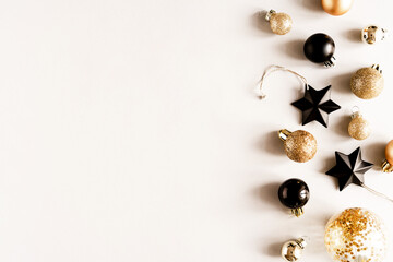 Flat lay of golden and black Christmas balls decorate on light background.