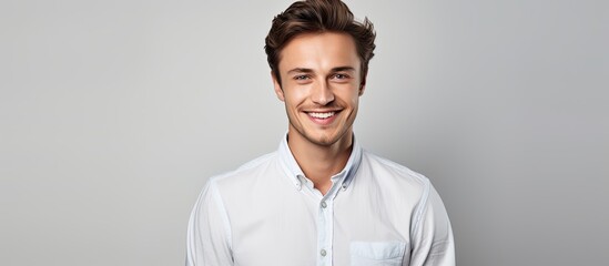 Obraz premium A person full of joy and youth wearing a white shirt making hand movements and maintaining eye contact with the camera while positioned against a neutral gray background