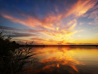 Stunning sunset on the shore of a lake with reeds in the foreground