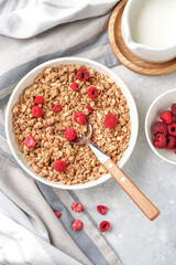 plate with muesli, with sublimated raspberries and nuts, light background, close-up
next to it is a bowl with raspberries and a glass with milk, top view
