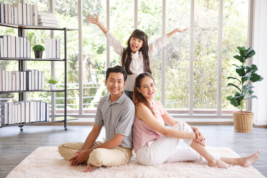 Real estate and mortgage concept : Family with child having fun in new home. Joyful first-time buyers in living room. Real estate, residential mortgage, moving into dream house.
